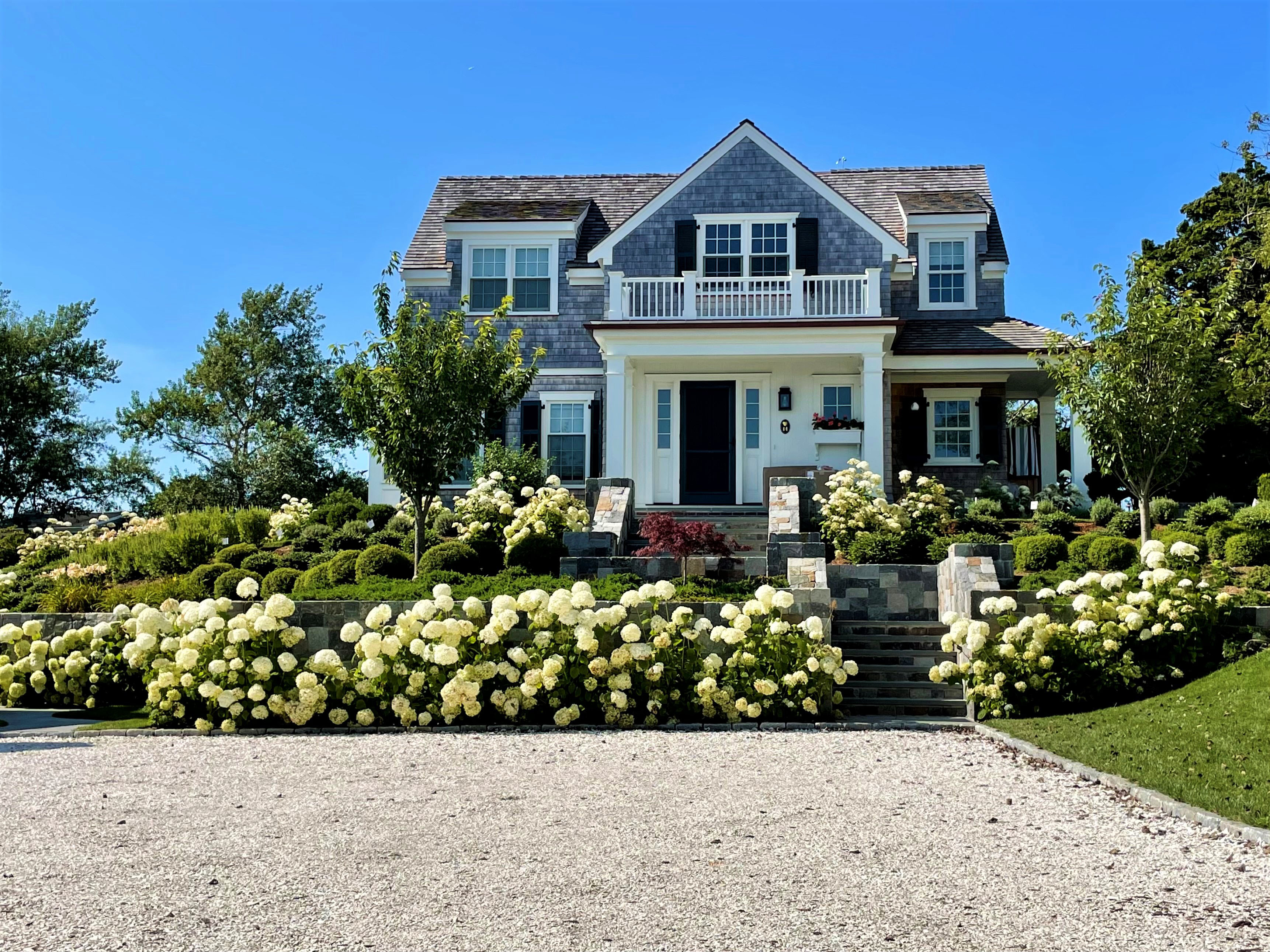 view of house with hydrangeas from driveway